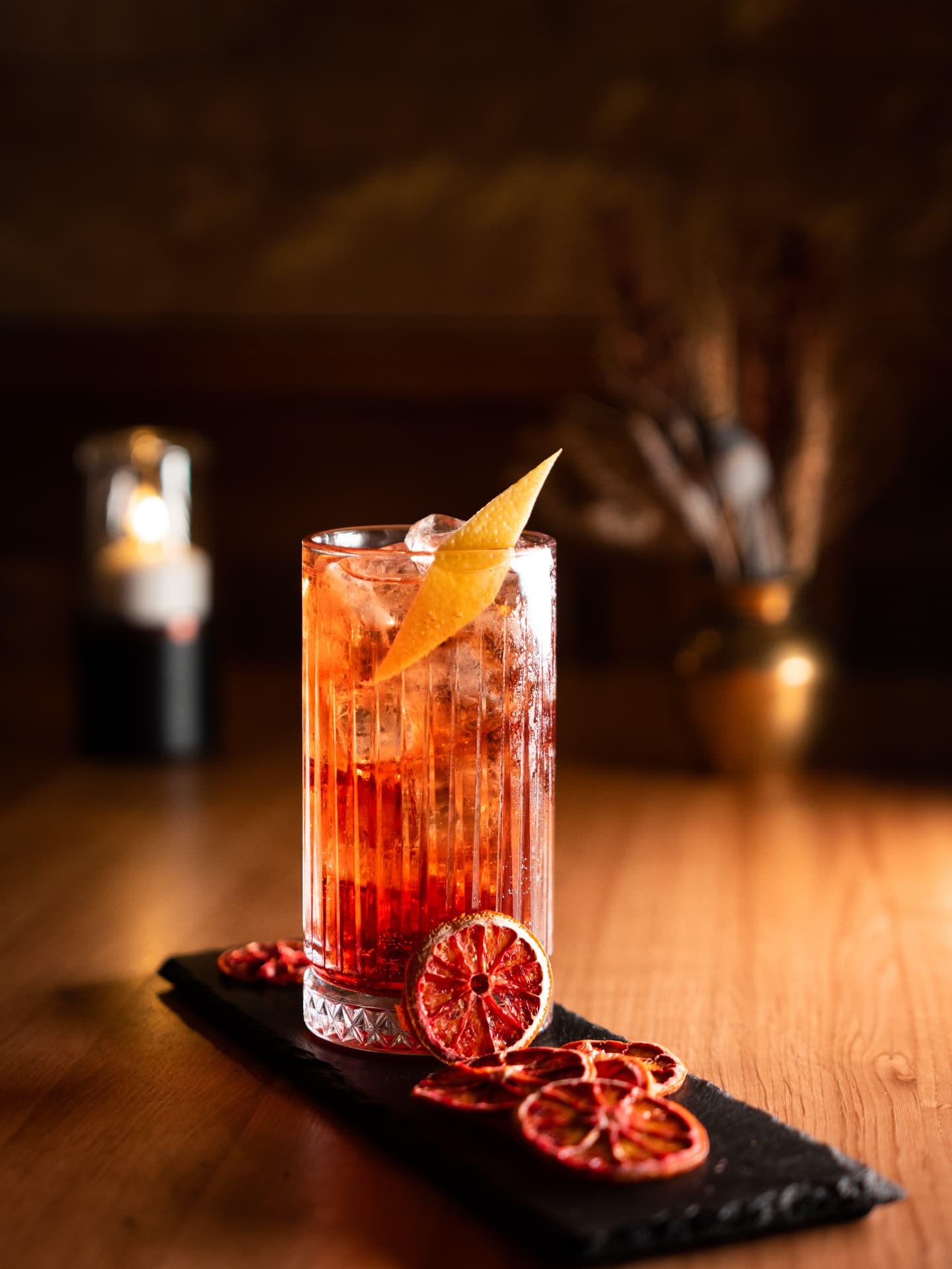Roter Aperitif-Cocktail mit Blutorangenscheiben auf Holztisch